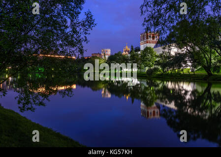 Village pittoresque vue de la nuit de Moscou avec le monastère de novodievitchi, murs de pierre blanche, vert des arbres, des lumières et de beaux reflets d'eux dans l'eau Banque D'Images