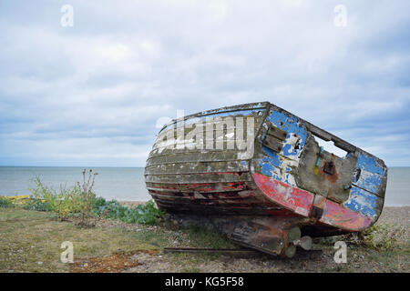 Ancien Bleu et rouge bateau cassé sur une plage de galets à Aldeburgh, Suffolk Banque D'Images