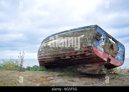 Ancien Bleu et rouge bateau cassé sur une plage de galets à Aldeburgh, Suffolk Banque D'Images