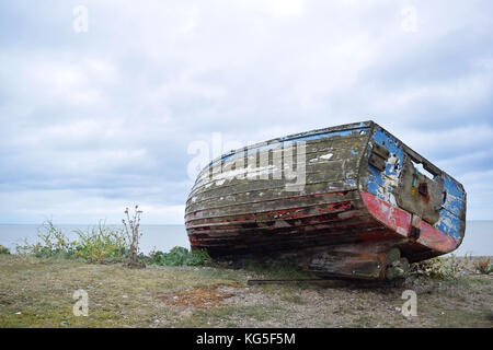 Ancien Bleu et rouge bateau cassé sur une plage de galets à Aldeburgh, Suffolk Banque D'Images