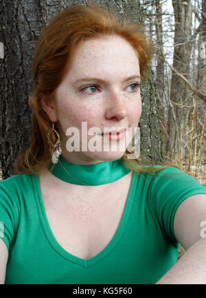 Jeune femme aux cheveux rouges avec des taches de rousseur en équipement vert Banque D'Images