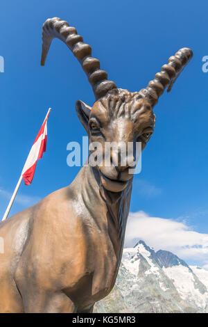 Le Grossglockner et le drapeau autrichien avec la statue en bronze d'un ibex alpin près de la hutte Kaiser Franz Josefs Höhe, Parc national de la haute Tauern, Carinthie, Autriche Banque D'Images