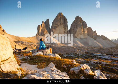 Un motard est relaxant en face de les trois sommets de lavaredo au cours d'un beau coucher du soleil, la province de Belluno, Veneto, Italie Banque D'Images