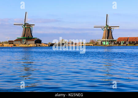 Les moulins à vent typiques reflètent dans l'eau bleue de la rivière Zaan au printemps Zaanse Schans les Pays-Bas Hollande du Nord Europe Banque D'Images