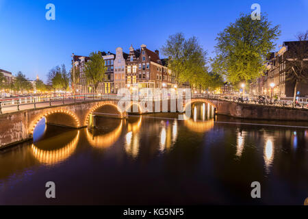 Crépuscule sur le feux de bâtiments typiques et les ponts reflétée dans un canal typique amsterdam hollande Pays-Bas europe Banque D'Images