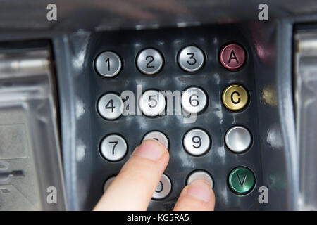 Une main appuyant sur un code PIN pour un virement bancaire avec une carte de crédit. Banque D'Images