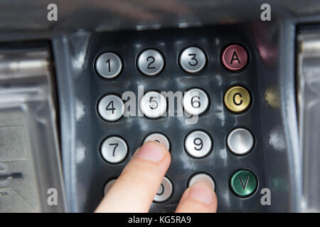 Une main appuyant sur un code PIN pour un virement bancaire avec une carte de crédit. Banque D'Images