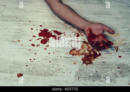 De sang sur un sol blanc. concept photo de meurtre et crime. les jeunes corps de l'homme sur le sol avec blessures sanglantes et du sang sur son bras et fermer un f Banque D'Images