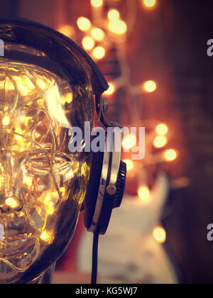 Casque sur une tête en verre avec des lumières de Noël, musique de Noël, la guitare rock avec des lumières à l'arrière-plan Banque D'Images