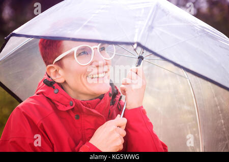 Portrait of smiling woman in imperméable et parapluie rouge Banque D'Images