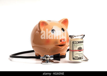 Cute tirelire avec stéthoscope noir et argent billets rouleau isolé sur fond blanc Banque D'Images