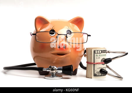 Cute tirelire avec stéthoscope noir et argent billets rouleau isolé sur fond blanc Banque D'Images