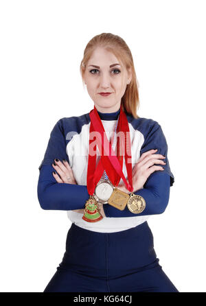 Une jeune femme athlétique assis avec les bras croisés et ses 4 médailles autour du cou, à la fière, isolée pour fond blanc Banque D'Images