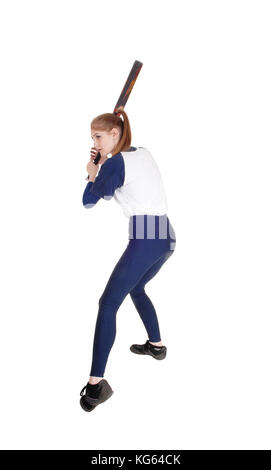 Une jeune femme slim jouer à la balle molle, balance son mauvais de frapper la balle dans un uniforme bleu, isolée pour fond blanc Banque D'Images