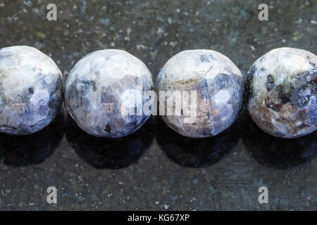 La prise de vue macro des eaux minérales naturelles rock specimen - collier de pierres labradorite gris foncé sur fond de granit Banque D'Images