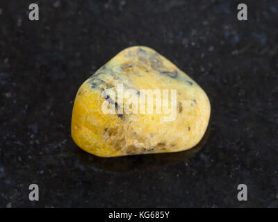 La prise de vue macro des eaux minérales naturelles rock specimen - tumbled agate jaune foncé sur fond de granit pierres du mexique Banque D'Images