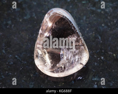 La prise de vue macro des eaux minérales naturelles rock specimen - quartz fumé poli sur fond de granit noir de pierre gemme Banque D'Images