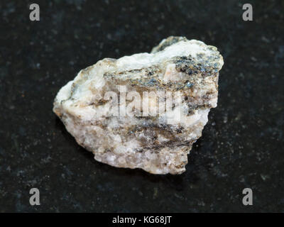 La prise de vue macro des eaux minérales naturelles rock specimen - gneiss rugueux pierre sur fond de granit sombre Banque D'Images