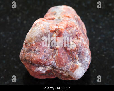 La prise de vue macro des eaux minérales naturelles rock specimen - pebble stone de pegmatite granitique sur fond sombre Banque D'Images