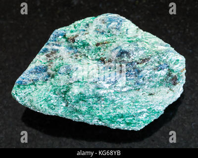 La prise de vue macro des eaux minérales naturelles rock specimen - rough fuchsite (chrome) mica sur la pierre de granit noir de l'arrière-plan hizovaara, république de Carélie dans Banque D'Images