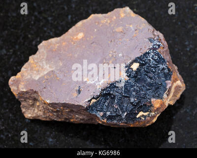 La prise de vue macro des eaux minérales naturelles rock specimen - agrégats de goethite sur la limonite sur pierre de granit noir de l'arrière-plan olkhinskoye mine, Irkoutsk regi Banque D'Images