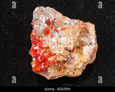 La prise de vue macro des eaux minérales naturelles rock specimen - cristal de la vanadinite sur pierres de granit sombre contexte du Maroc Banque D'Images