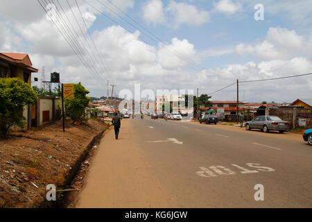 Panorama de la rue de Segou dans l'Etat d'Ondo, au Nigeria, avec des voitures et des gens qui marchent à côté des maisons Banque D'Images