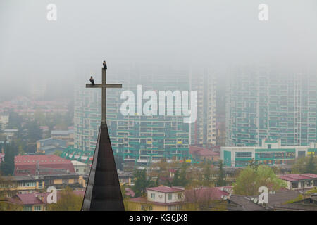 Vue aérienne de la croix de l'église sur l'arrière-plan des immeubles à appartements dans le brouillard du matin, Sochi, Russie Banque D'Images