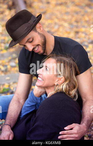 Jeune beau couple assis dehors sur les voies ferrées et serrant les uns les autres Banque D'Images