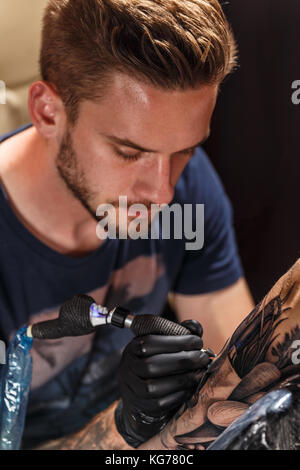 Close up tattoo artiste démontre le processus de tatouage noir Banque D'Images