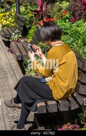 Femme à l'aide de smart phone à hong kong park, central, hong kong Banque D'Images