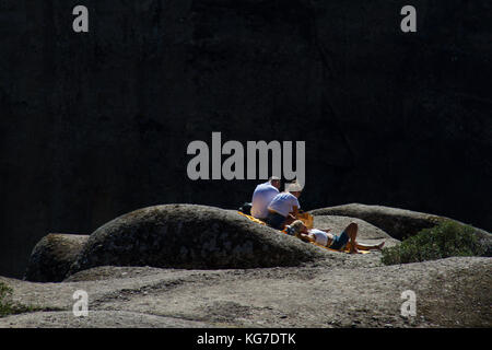 Météores, Grèce - 9 octobre 2017 : un homme et deux femmes se reposant et prenant un bain de soleil sur l'un des rochers du monastère rocheux des Météores en Grèce Banque D'Images