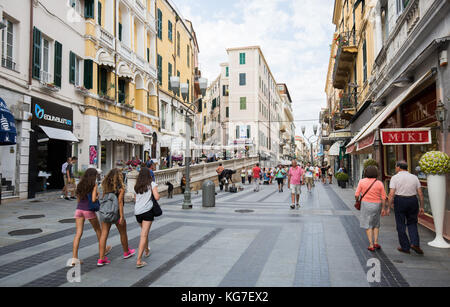 Les gens marchent sur la via Giacomo Matteotti, bâtiment de magasin à côté de la passerelle piétonne, San Remo, Italie. Banque D'Images