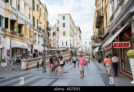 Les gens marchent sur la via Giacomo Matteotti, bâtiment de magasin à côté de la passerelle piétonne, San Remo, Italie. Banque D'Images