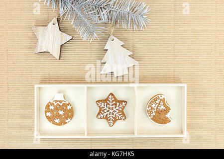 Gingerbread cookies faits maison de Noël et de l'argent firtree branche avec décorations en bois sur fond de papier brun Banque D'Images