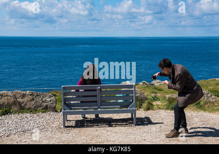 La fin des terres, Angleterre - 27 avril 2017 : les touristes assis sur un banc au premier/dernier house à la fin des terres en été pour prendre des photos avec votre téléphone. Banque D'Images