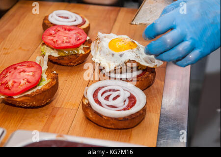 Le cuisinier en chef préparation des burger dans la cuisine.burger restaurant menu cuisson. Le cuisinier ingridients mis ensemble par des couches. fast food cafe c Banque D'Images