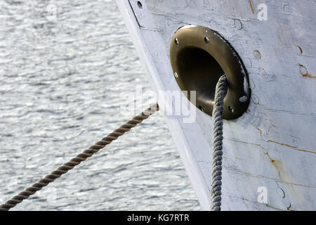 Des cordes attachées à un mur du port et affirmation d'un hawsepipe ou chaumard laiton sur un arc d'immobiliser des navires. d'un navire à quai ou de l'amarrage d'un bateau dans le port. Banque D'Images