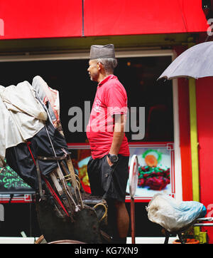 Nepali est son rickshaw en attente de passager à thamel street de Katmandou. Banque D'Images