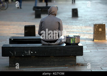 Sweat à capuche immigrant réfugié avec un pot de cuisine nouvellement acheté assis sur un banc de la rue vu de derrière Sauchiehall Street, Glasgow, Glasgow City, Banque D'Images