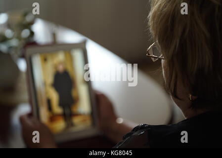 Femme adultes assis à la table est titulaire d'ordinateur numérique comprimé et à ses photos sur l'écran de l'ordinateur tablette. close-up Banque D'Images