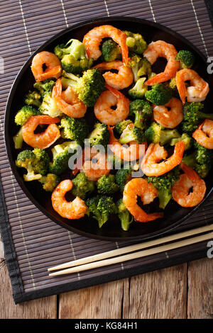 L'alimentation saine : crevettes Brocolis sautés avec gros plan sur une assiette. vertical haut Vue de dessus Banque D'Images