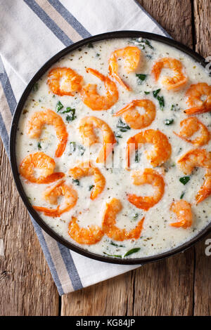 Crevettes épicées épinards avec sauce au fromage crémeux en close-up sur une plaque sur une table. vertical haut Vue de dessus Banque D'Images