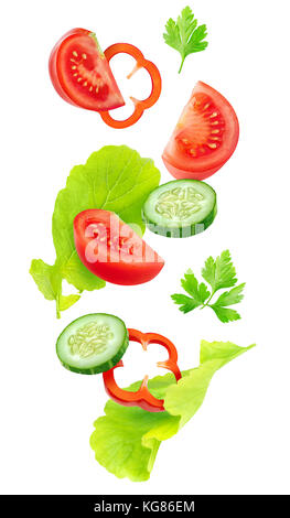 La baisse isolée des légumes. tranches de tomate, concombre, poivron rouge et feuilles de laitue salade fraîche (ingrédients) dans l'air isolé sur bac blanc