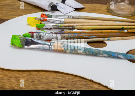 La palette d'art avec des pinceaux d'art avec orange, jaune et vert sur fond de bois Peinture Banque D'Images