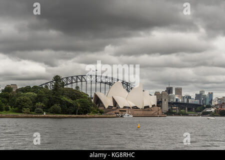 Sydney, Australie - 23 mars 2017 : blanc Opera House et Harbour Bridge de bow noir sous des pluies lourdes. cloudscape kirribilli immeubles de grande hauteur à l'arrière. Banque D'Images