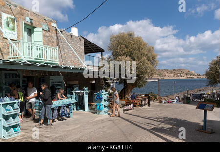 Boutique de souvenirs dans la station balnéaire de Plaka avec vue sur l'île de Spinalonga, ancienne colonie de Leper. Nord de la Crète, Grèce. Octobre 2017 Banque D'Images