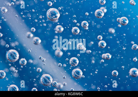 Grandes belles bulles d'oxygène sous l'eau sur un fond bleu macro. Mouvement des bulles d'oxygène dans un liquide à l'éclairage du studio. Belle structure Banque D'Images