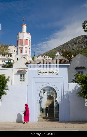 Une femme arabe marche dernières mosquée à Chefchaouen, Maroc Banque D'Images