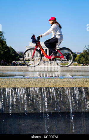 Cycliste féminine équitation un capital Bikeshare location avec l'Abraham Lincoln Memorial en arrière-plan, Washington, DC, United States of America, USA. Banque D'Images